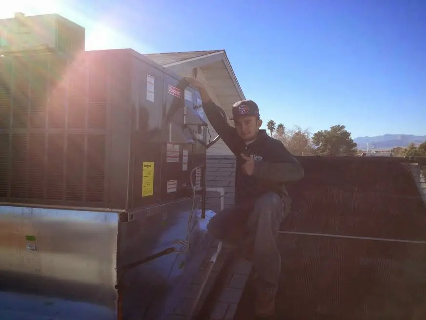 HVAC technician performing AC Tune-Up on a rooftop unit in Mobile